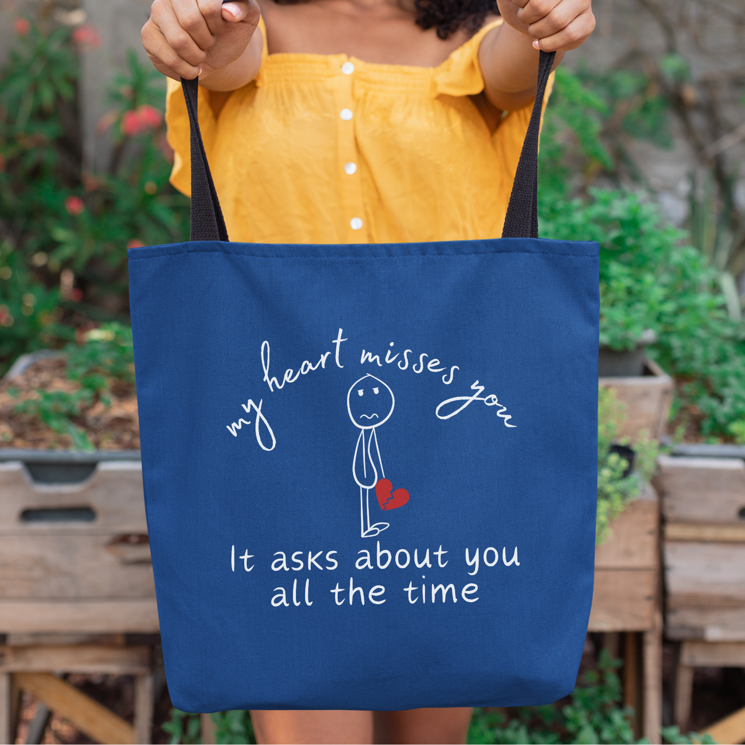 Blue tote bag with the message "My Heart Misses You. It Asks About You All The Time," featuring a sad stick figure holding a broken heart. 