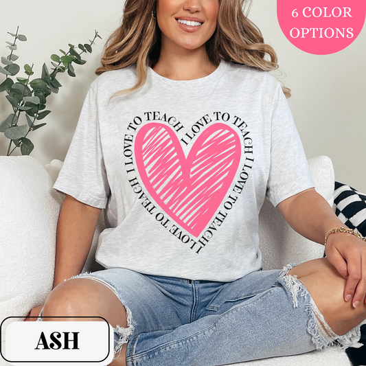 Ash Bella Canvas 3001 T-shirt with a large heart graphic in pink with the words "I love to teach" surrounding the heart. Makes a great gift for a teacher, or for teachers to wear for Valentine's Day.