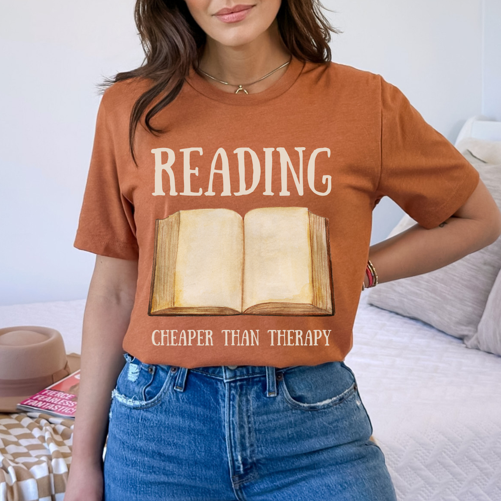 Heather Autumn Bella Canvas 3001 T-Shirt that says "Reading Cheaper Than Therapy" with a large old fashioned book graphic. Perfect gift for literary enthusiasts, bookish girlfriends, reading or English teachers, and reading lovers.