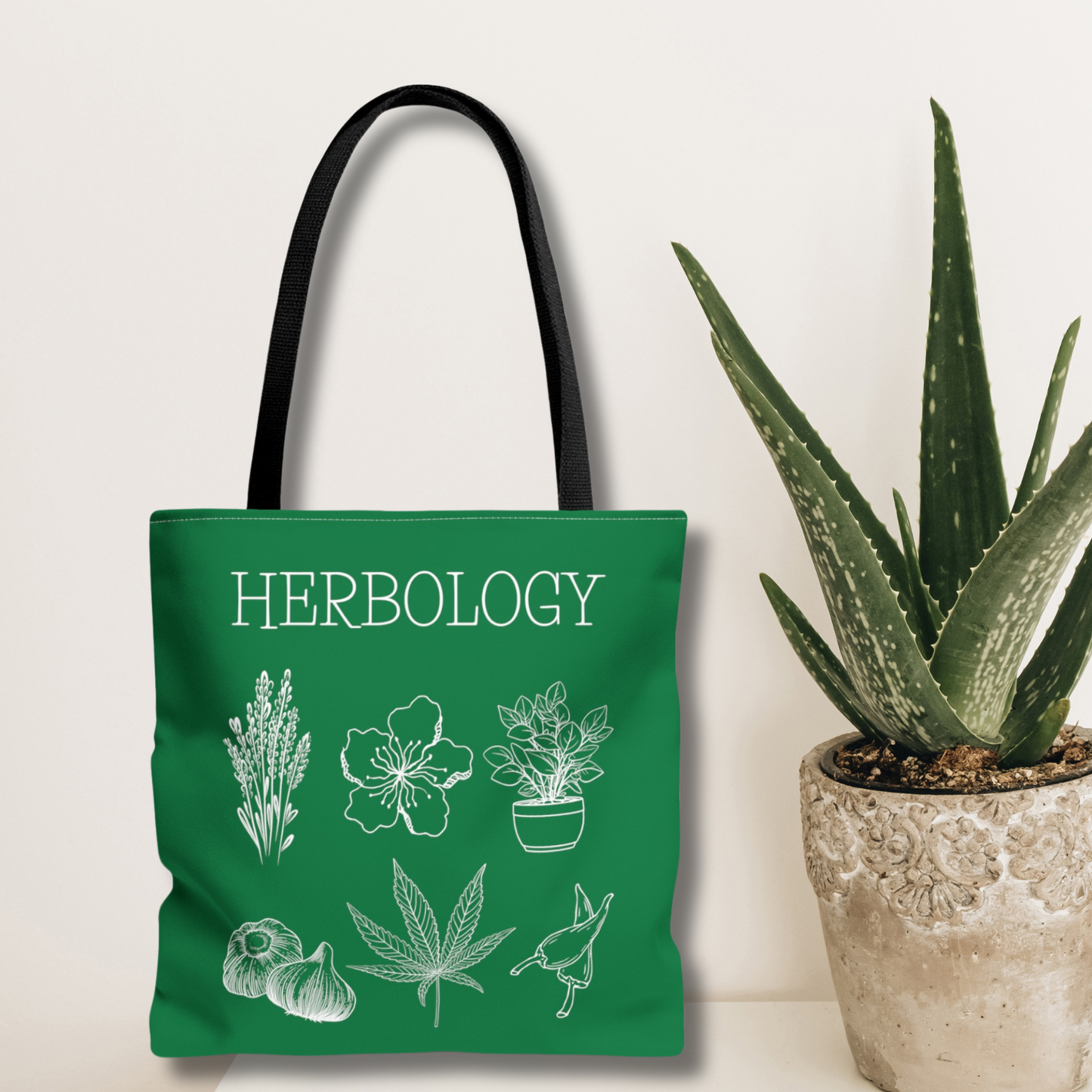 Magical Herbology tote bag inspired by hogwarts classes. Features a simple design of flowers, herbs and plants. Bag is green with a black handle.