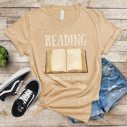 Heather Sand Dune Bella Canvas 3001 T-Shirt that says "Reading Cheaper Than Therapy" with a large old fashioned book graphic. Perfect gift for literary enthusiasts, bookish girlfriends, reading or English teachers, and reading lovers.