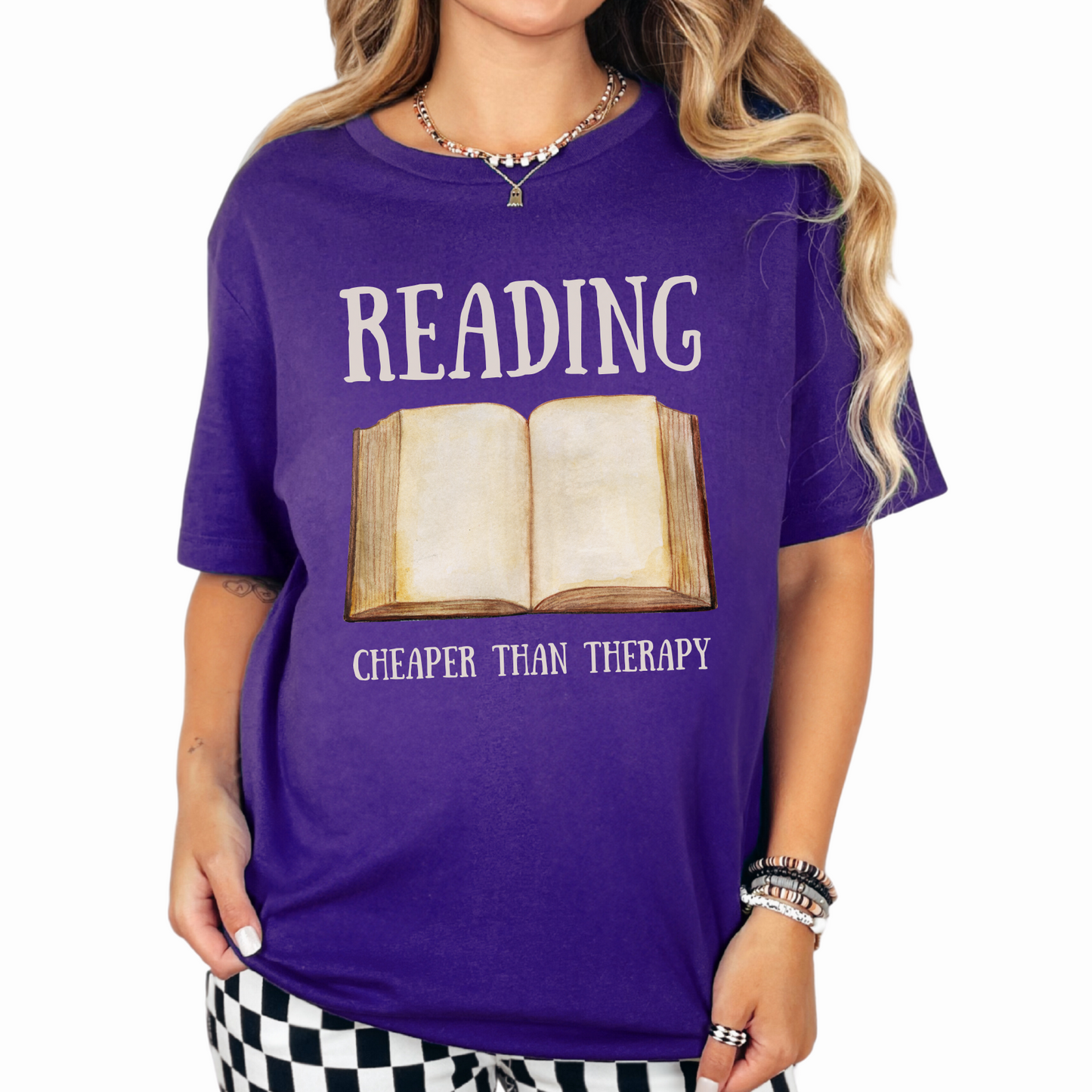 Team Purple Bella Canvas 3001 T-Shirt that says "Reading Cheaper Than Therapy" with a large old fashioned book graphic. Perfect gift for literary enthusiasts, bookish girlfriends, reading or English teachers, and reading lovers.