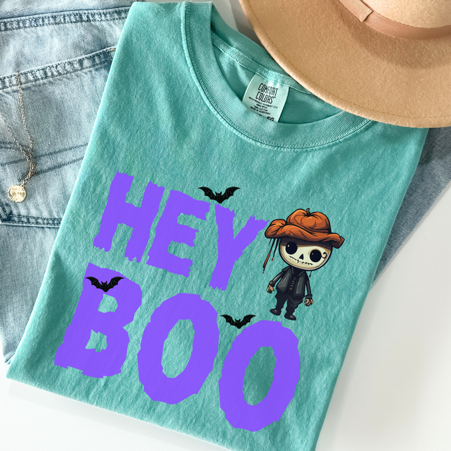 Sea foam Comfort Colors Halloween t-shirt from our Hey Boo Collection, featuring a cute pumpkin-head skeleton and bats graphic.