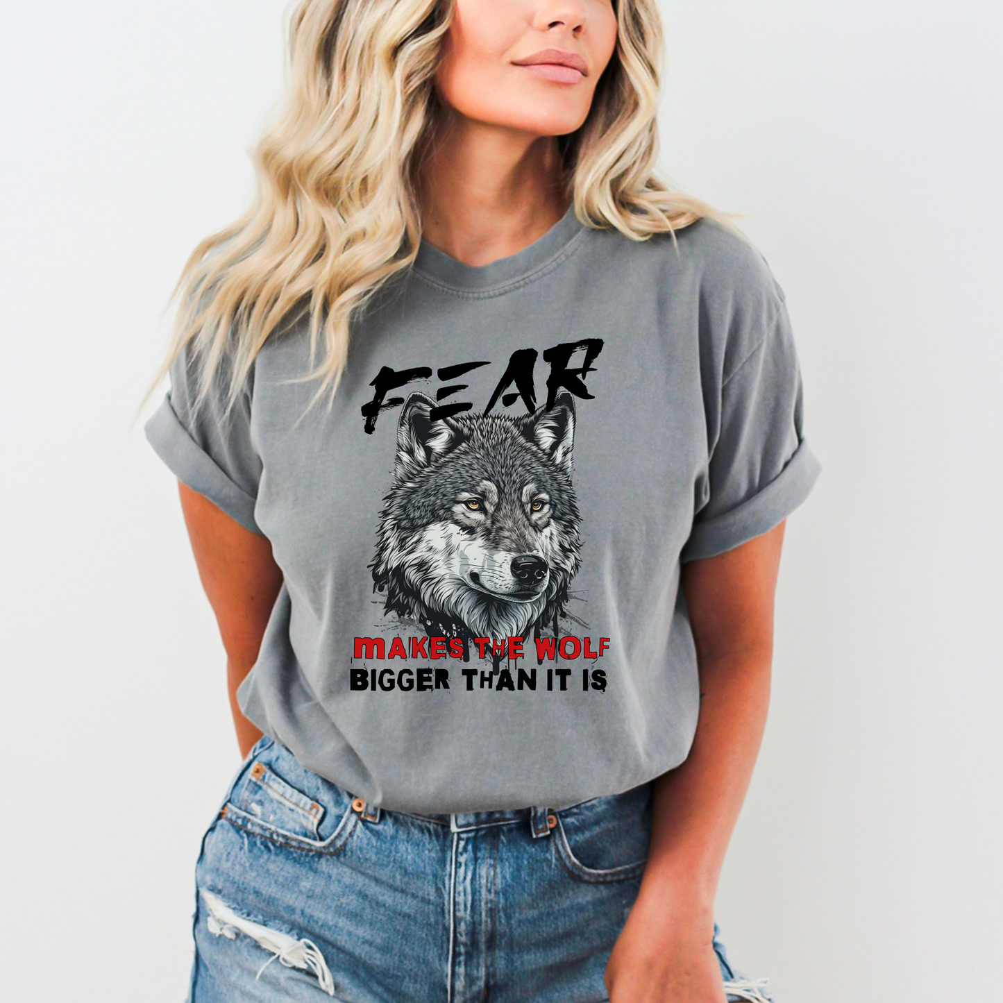 Gray Comfort Colors t-shirt with a wolf graphic and the phrase: Fear Makes The Wolf Bigger Than It Is. Ideal gift for anyone struggling with fearful challenges to motivate and inspire. 